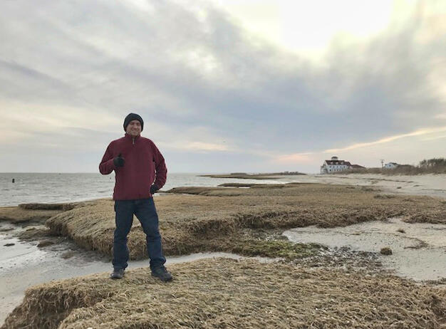 A man stands on a coastline near the water