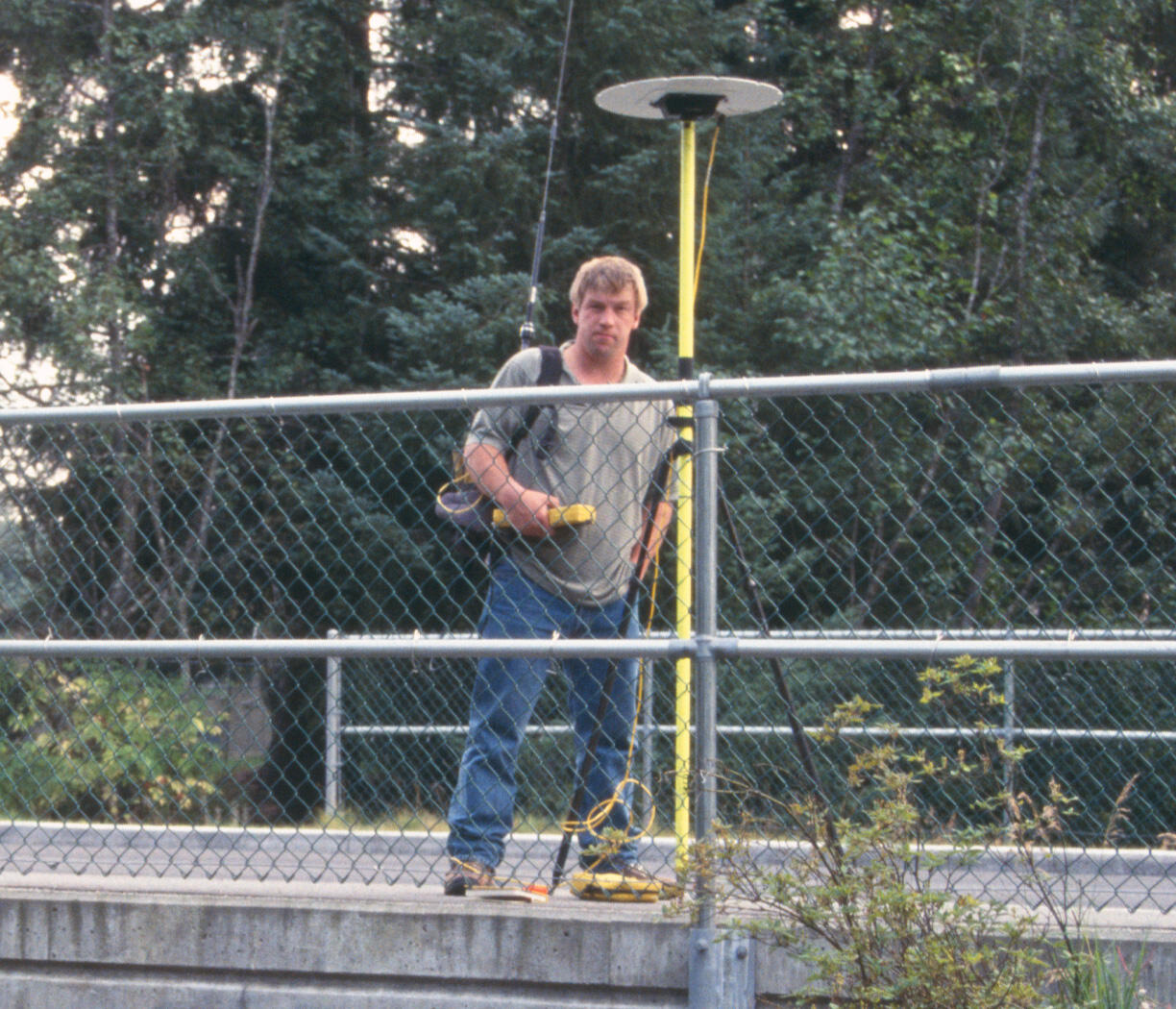 Dan Long on a bridge over Duck Creek next to a GPS receiver in Juneau, Alaska 
