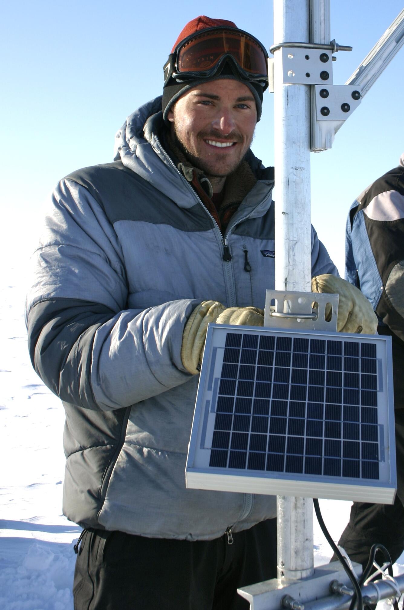Daniel McGrath attending equipment with a solar panel in Alaska