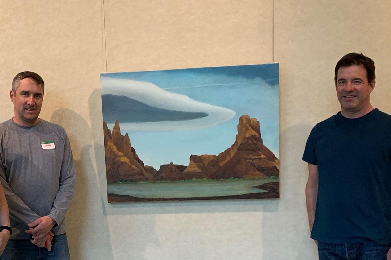 two gentlemen standing on sides of painting hanging on wall