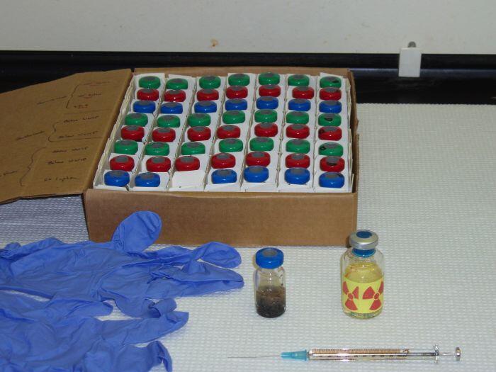 Glass serum vials (bottles in the foreground and in the box) are used to construct microcosms