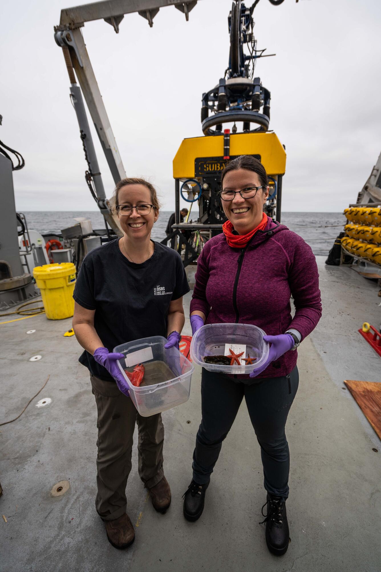 Image shows two women standing on a ship deck holding samples