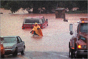 Picture of tow truck driver assisting car stuck in flood waters.
