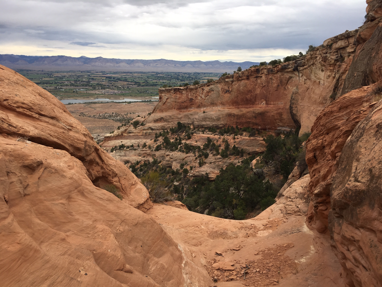 photograph taken on a cloudy day looking through the Fruita Dugway with rock faces on either side and canyonland ahead