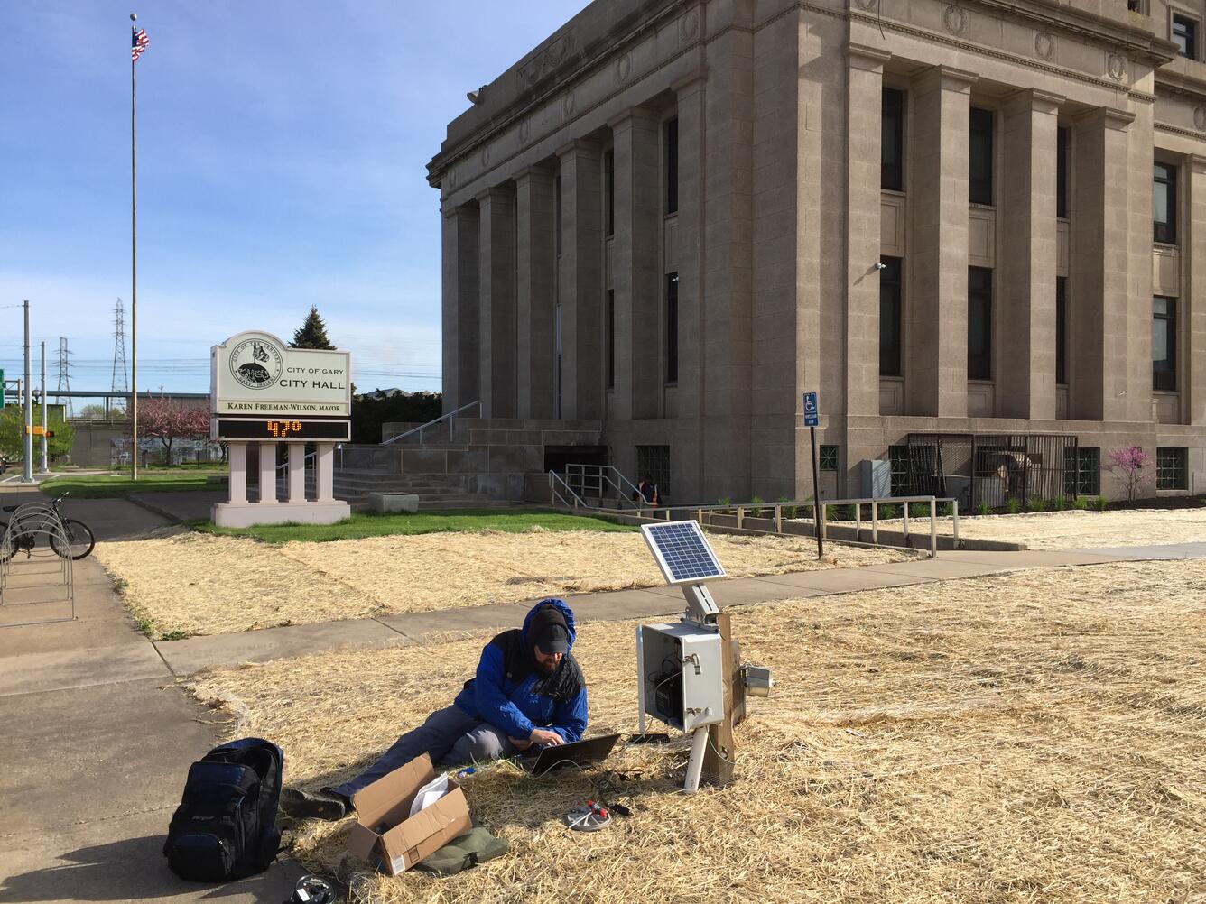 Photo of a USGS scientist taking readings from a Gary City Hall groundwater monitoring well.