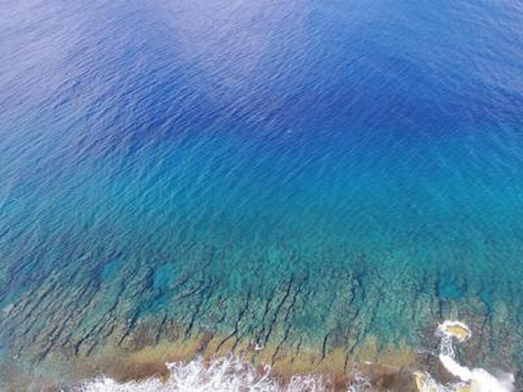 Aerial shot of the clear blue ocean off the coast of Guam.