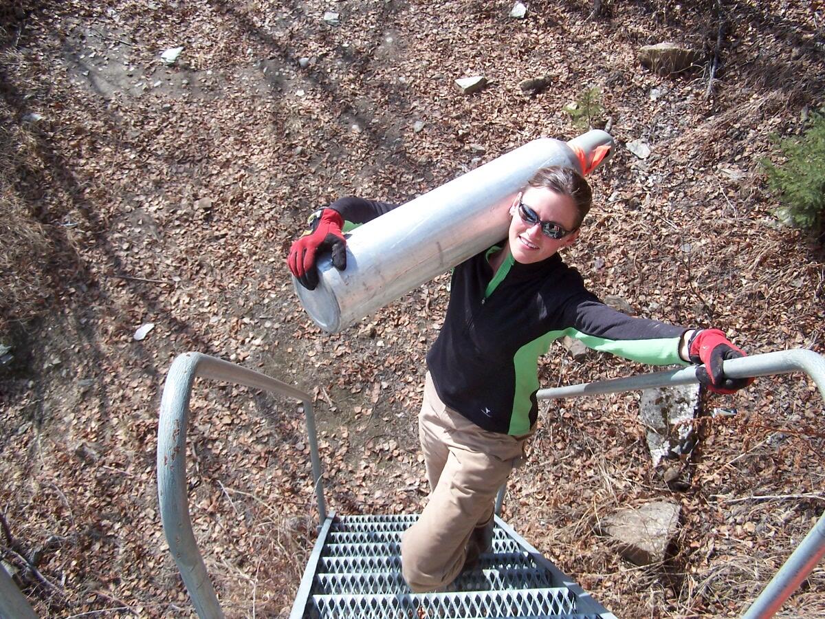 Heather Best carrying a propane tank up a ladder