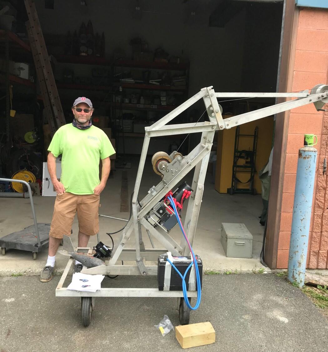 man in usgs shirt standing next to a variable rate sediment sampler