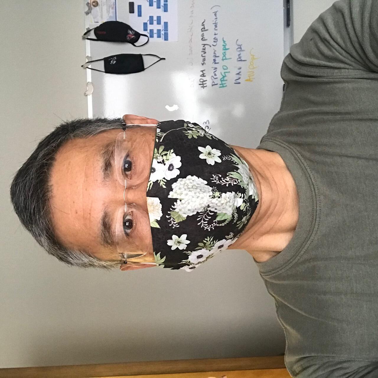 Photo of Hon Ip wearing a black and white cloth face mask.