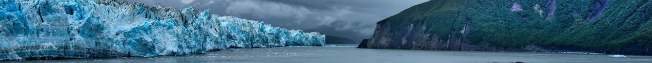 Panorama of Alaskan coastline with Hubbard Glacier on the left and hills on the right