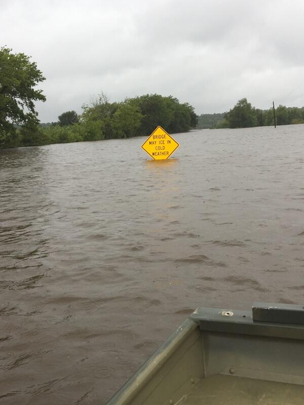 Image shows a partially submerged street sign from a flooded river