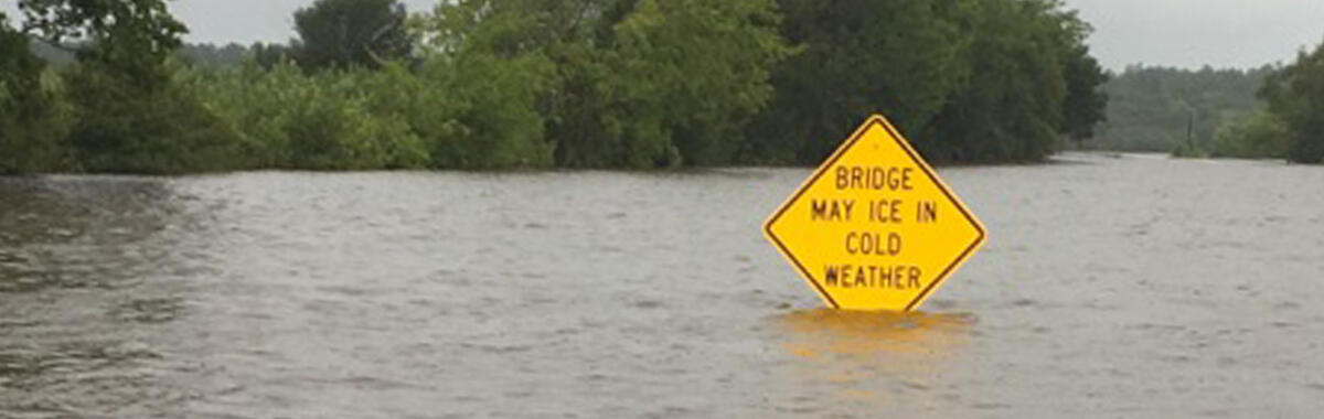 A photo of floodwaters reaching up to a street sign in Texas