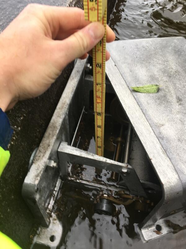 Image shows a USGS scientist with a tape measure at a flooded streamgage