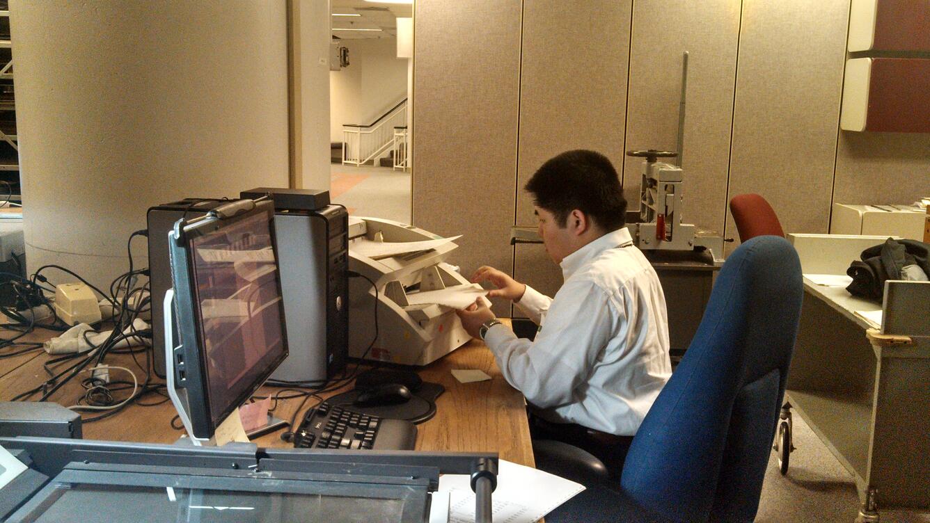 young man working at a desk with computer and printer