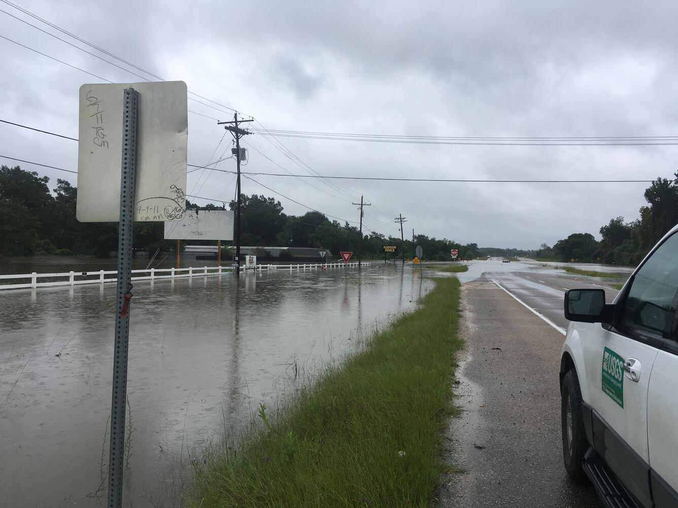 Image shows a flooded street with a USGS truck nearby