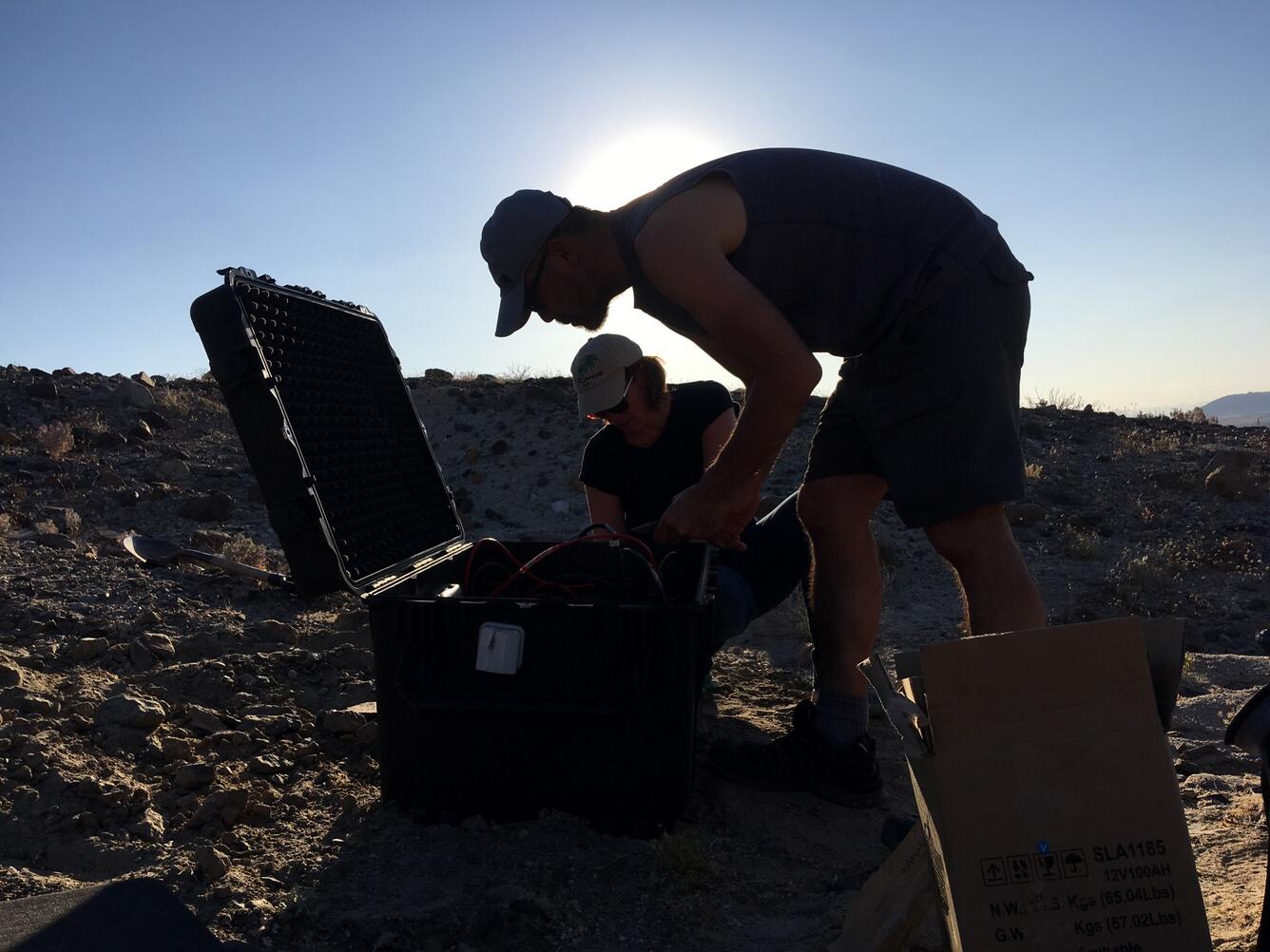 Image shows people silhouetted by the sun working in the desert