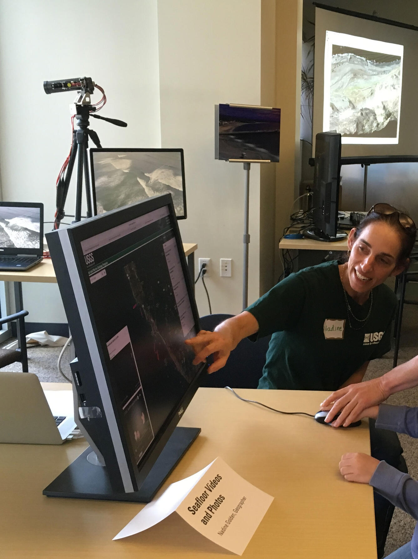 A USGS employee describes what is shown on the computer screen while visitors use a computer with a mouse.