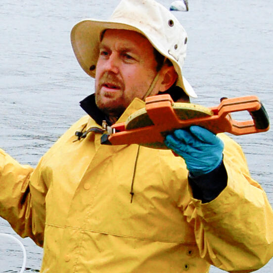 John Crusius in waist deep water with a large measuring tape