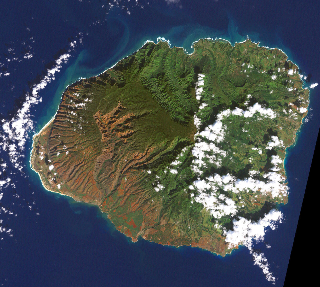 Aerial view of an island with clouds floating above it, with distinctive land features like mountains and agriculture.