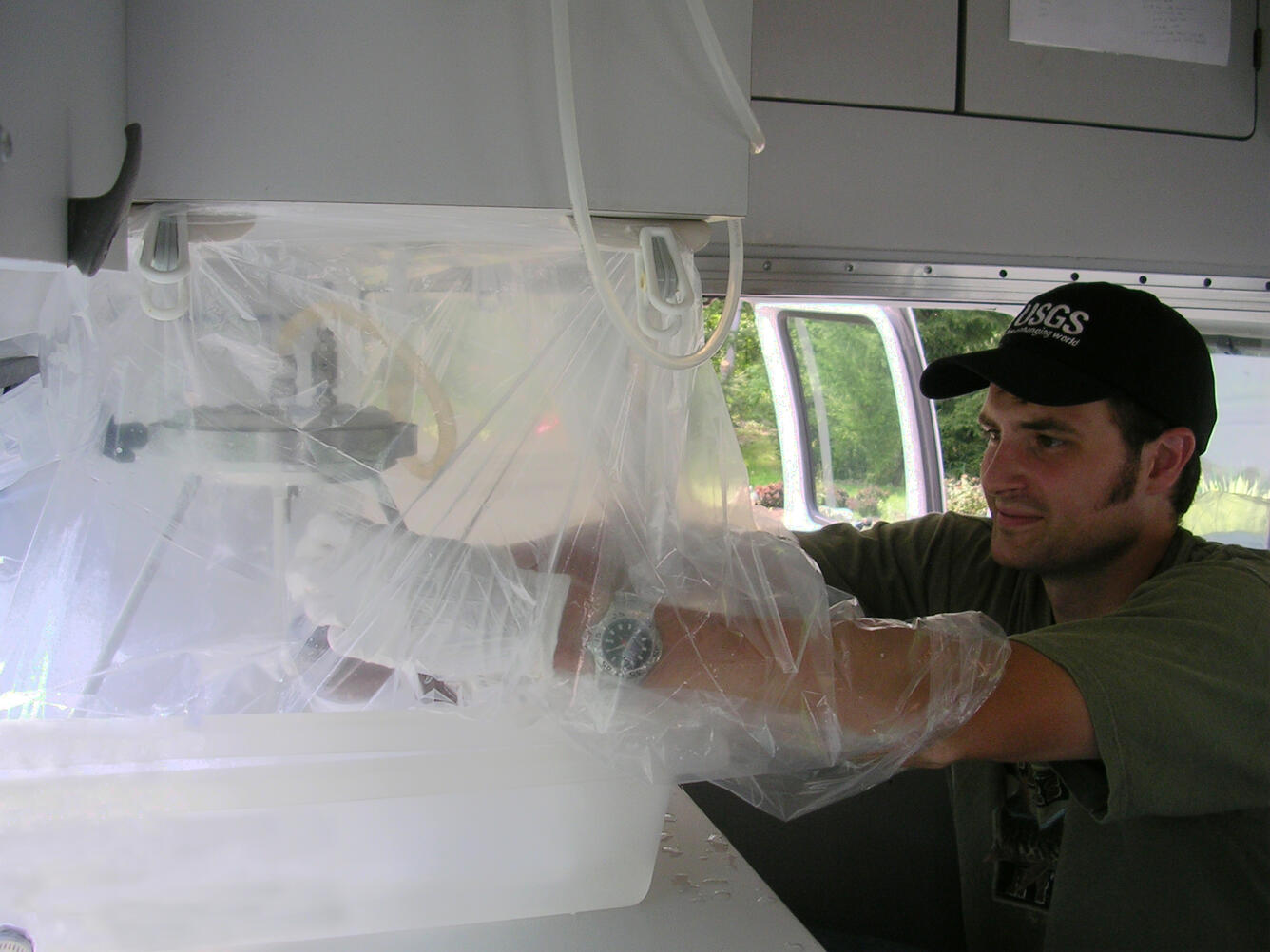 USGS Hydrologist examining water collection using specialized equipment.