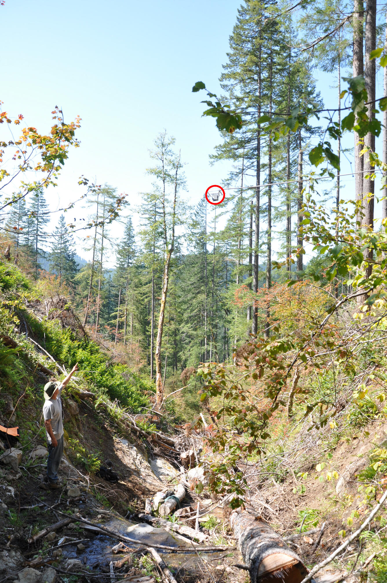 Data logger suspended above a channel with a person pointing up at it from the bottom of the channel