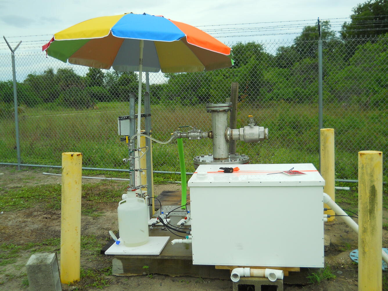 Photo of sample site showing equipment in a field covered by a colorful umbrella.