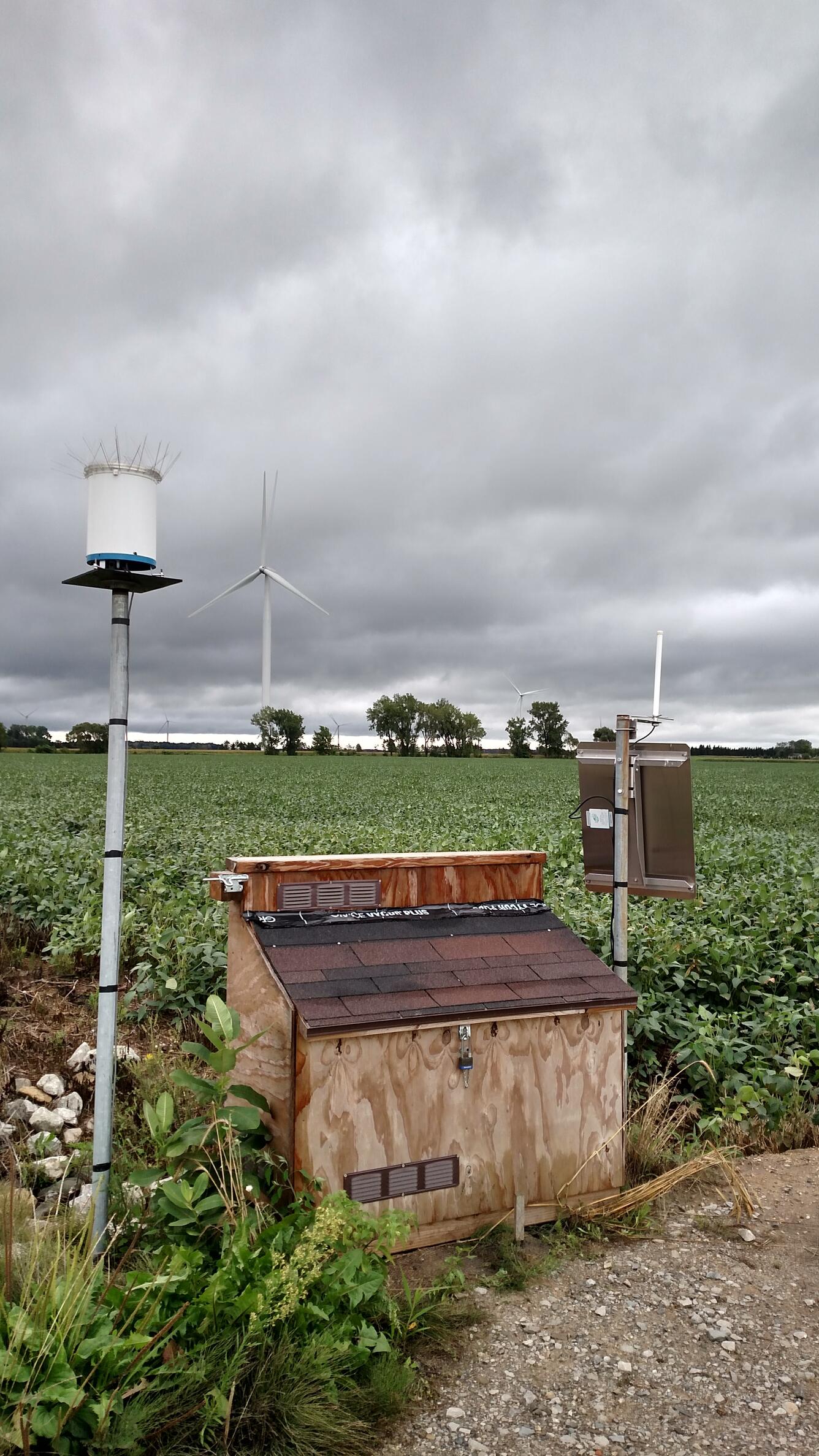 Equipment enclosure and rain gage by agricultural field in Michigan