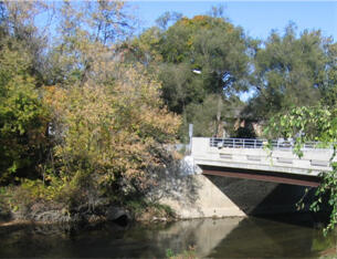 Bridge over river in late summer, trees just starting to change to fall colors.