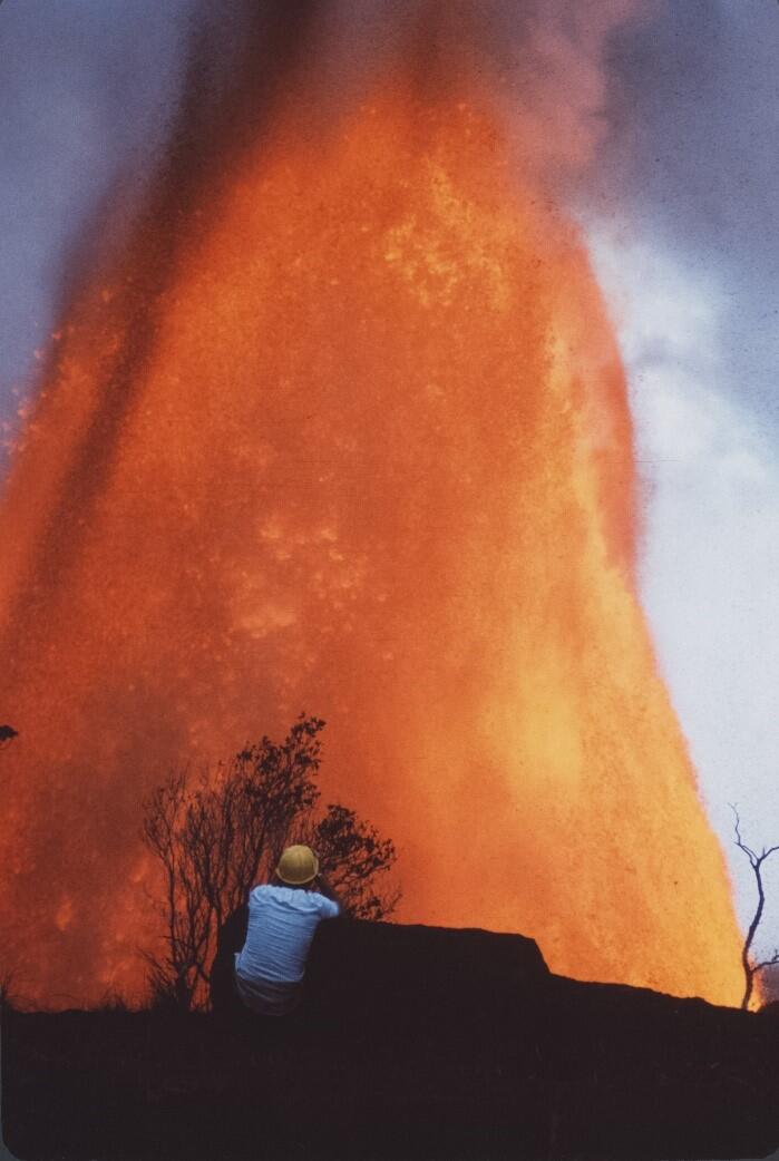 Color photograph of lava fountain with scientist in the foregroung