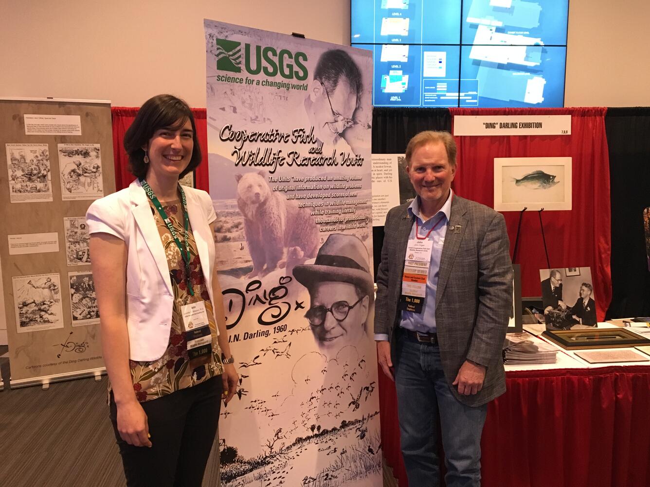 Two biologists stand in front of USGS sign for The Wildlife Society Annual Meeting