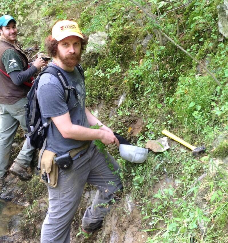 Ryan McAleer collecting samples from the base of an outcrop