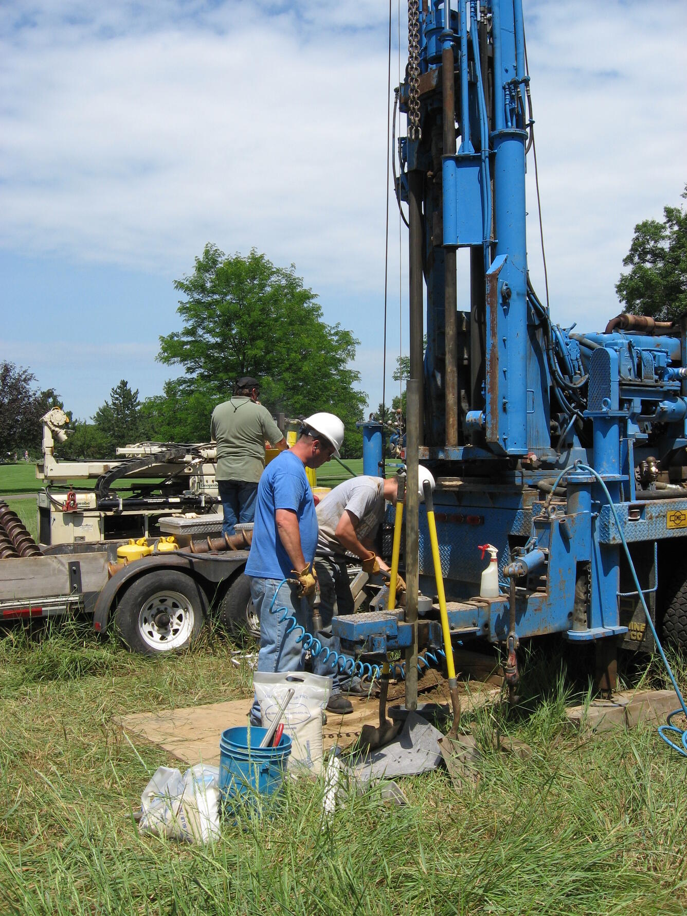 Complicated groundwater drill rigs mounted on big trucks and their crew.