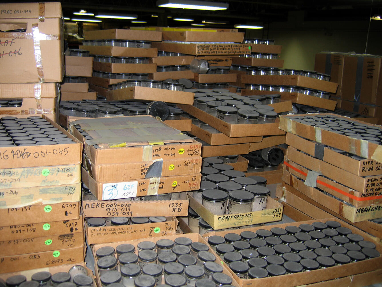 Dusty and disorganized sample jars in cardboard boxes.