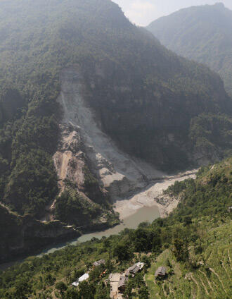 light brown rock slide on forested mountain with river below