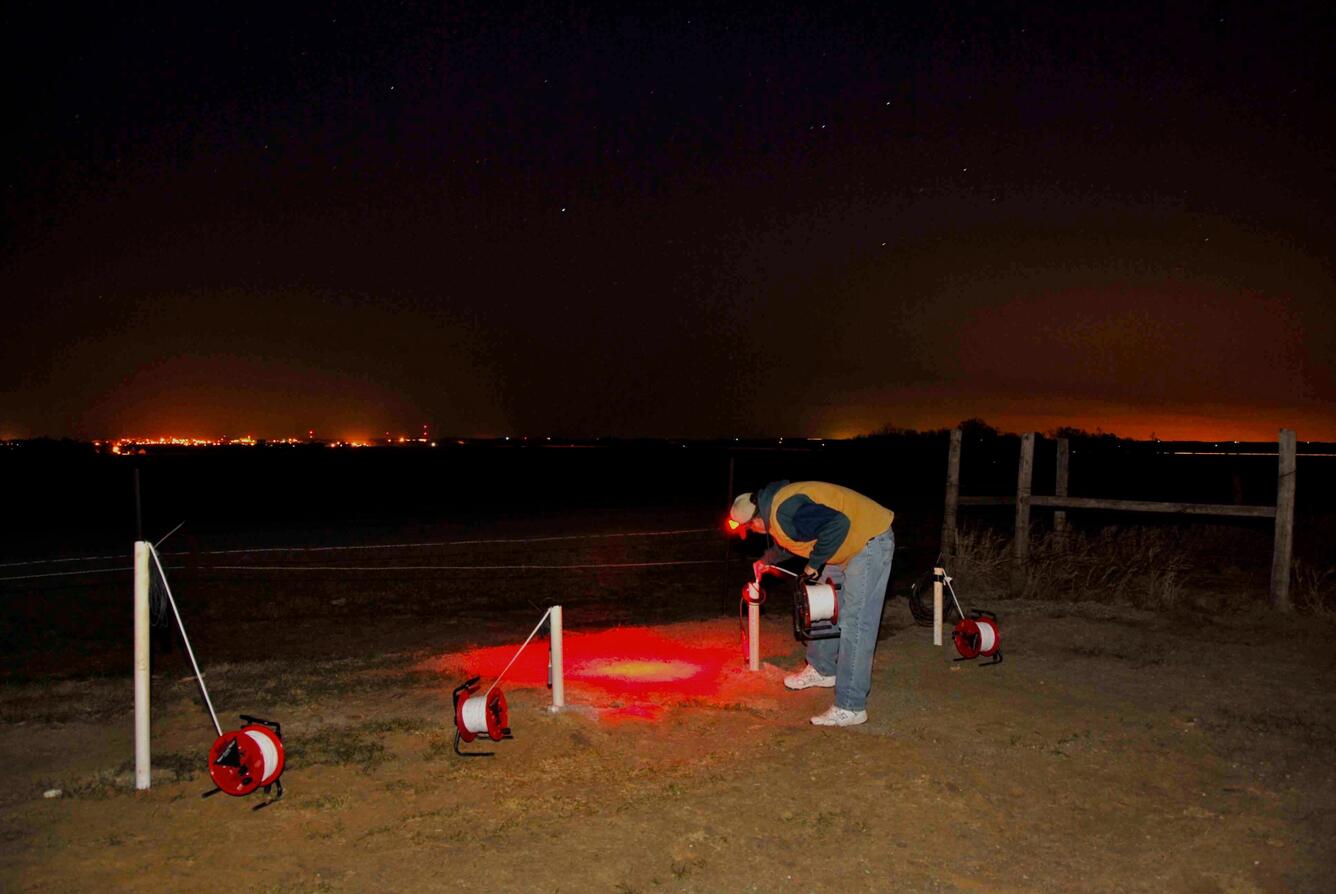 Photo of scientist measuring groundwater levels at night.