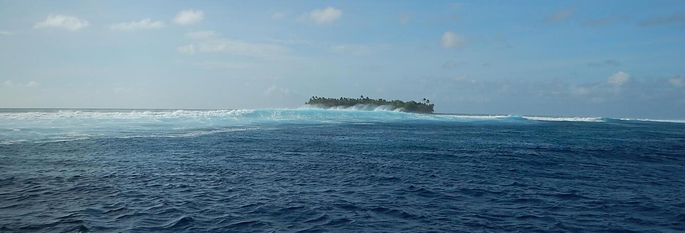 Waves brush past a low-lying island off the shore of Kwajalein Island.