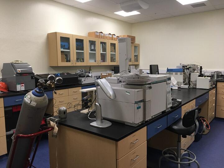Photo of a laboratory with lots of equipment on the countertops and a tank of gas.