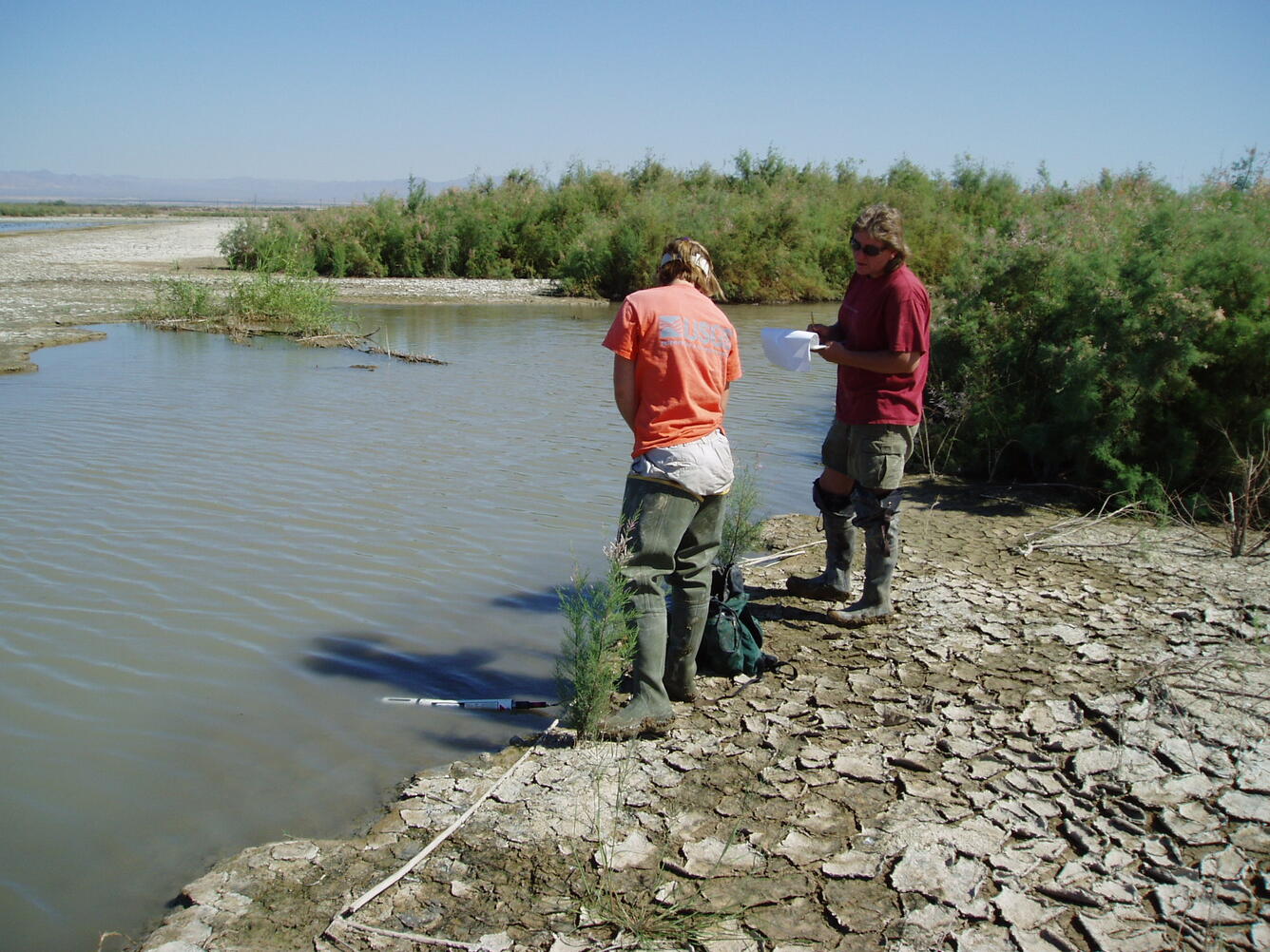 Scientists stand at the edge of the Salton Sea testing the quality of the water.