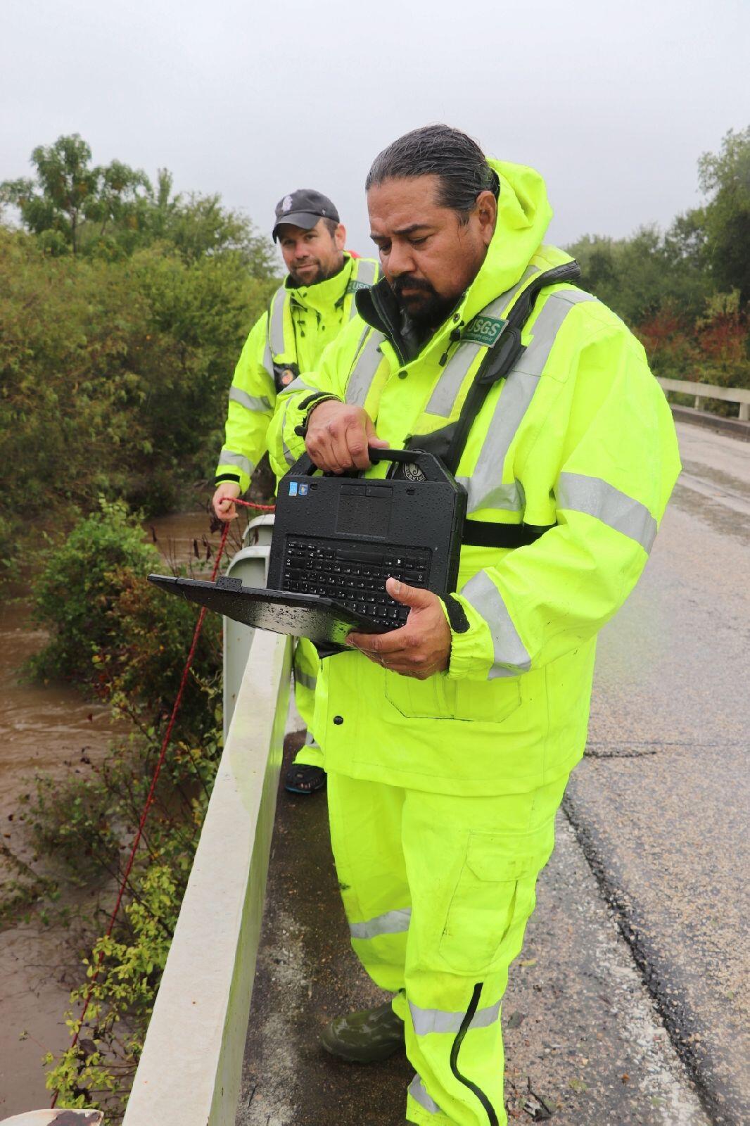 USGS scientists in PFDs measure flooding along an elevated highway in Texas