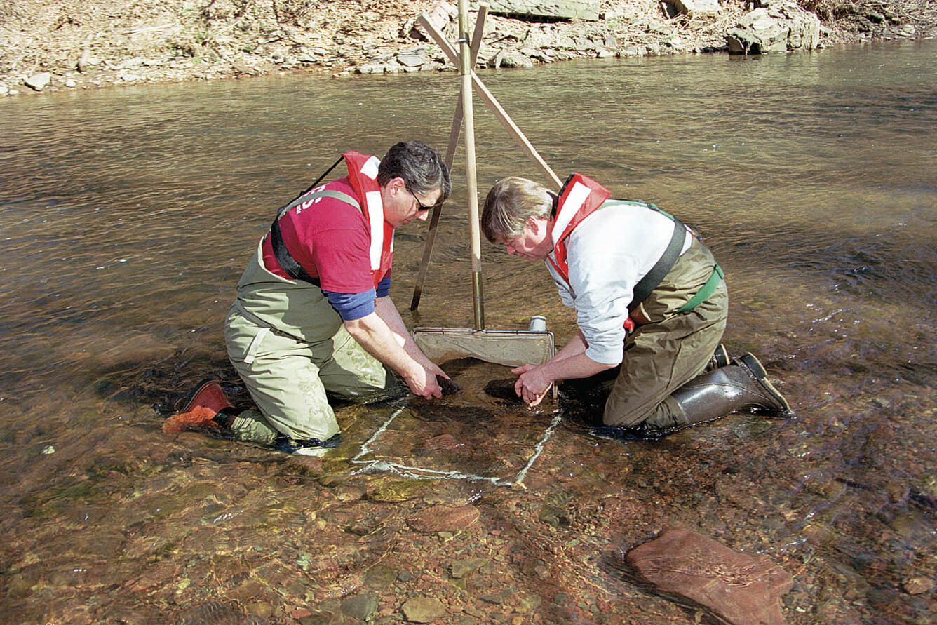 Two USGS scientists collecting samples from the river bed