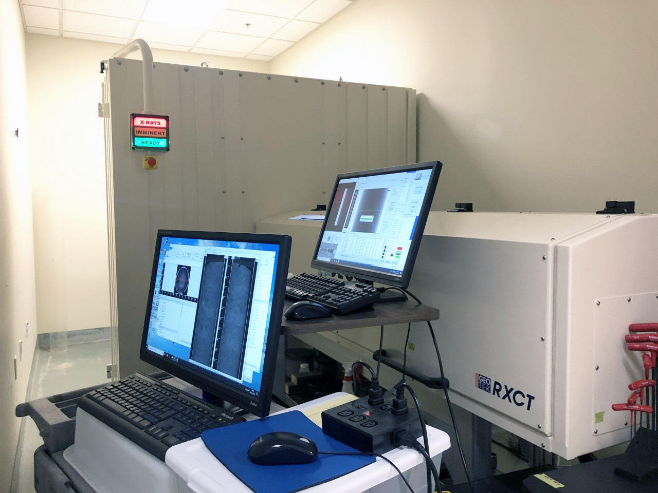 Photograph of a laboratory with a big x-ray machine and two computers for calibration and visualization.