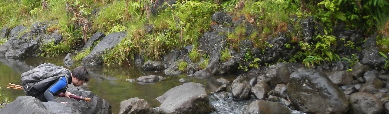 Man wading in stream carrying equipment
