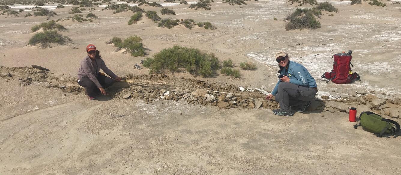 two women keeling on ground near earth rupture