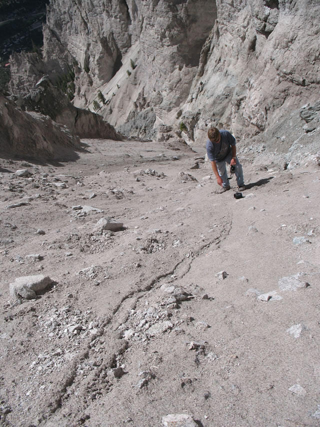View of Chalk Cliffs down-channel where the debris flow is originating from with a man standing on side for scale