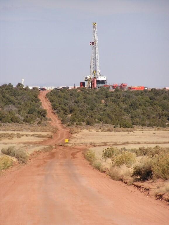 Drill rig in the distance off a dirt road in a semi-aid system