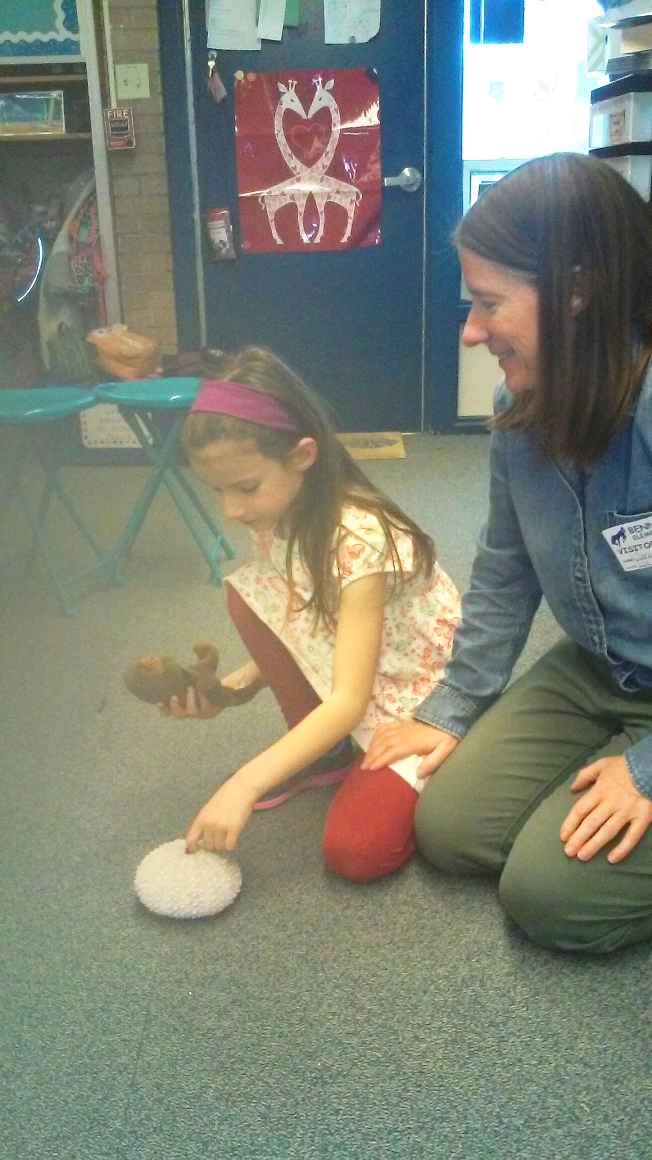 Scientist Sarah Carter shows first grader Hazel how sea otters and sea urchins interact.