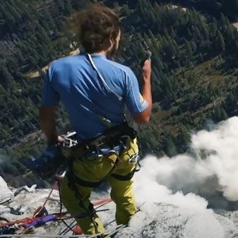 guy standing on cliff edge watching rockfall below