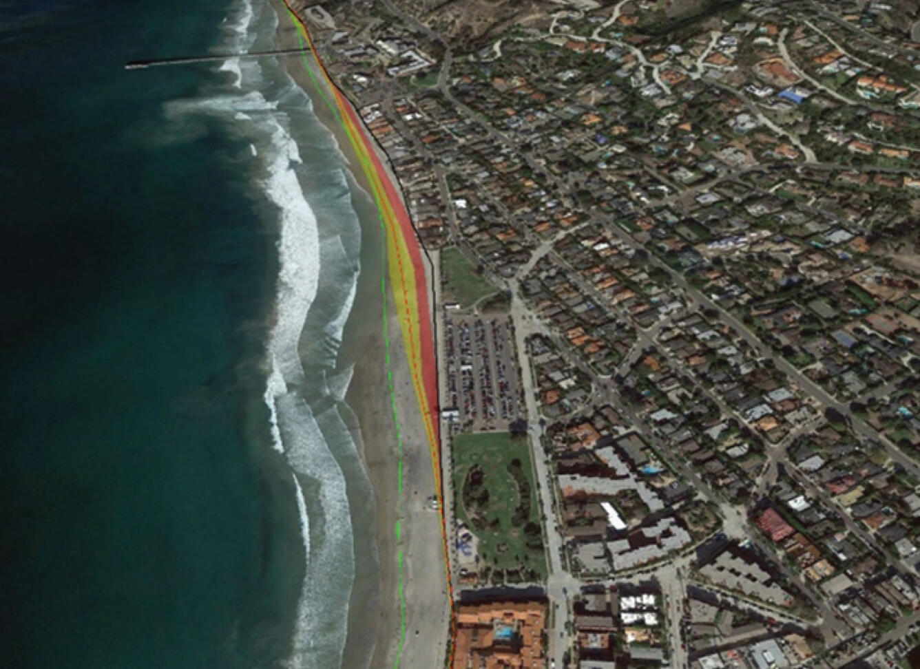 View from the sky looking down on a coastal town with a sandy beach and buildings.