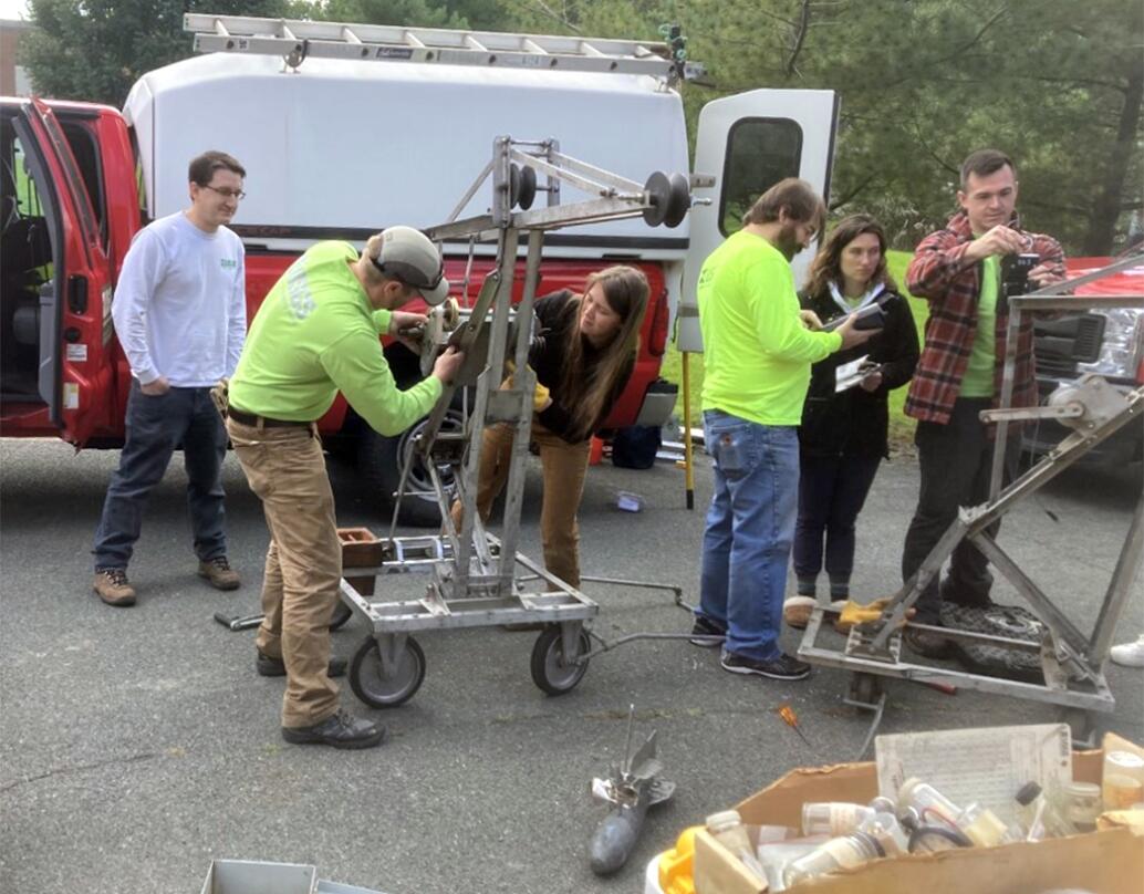 6 people beside a truck next to and working on several large pieces of USGS equipment