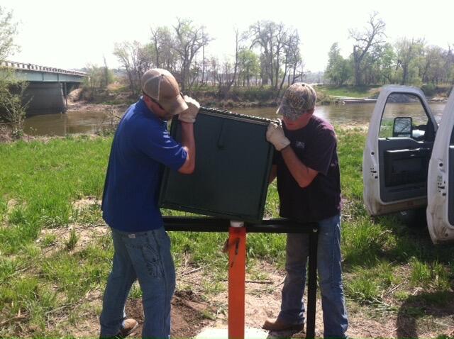Photo of technicians installing monitoring well shelter.